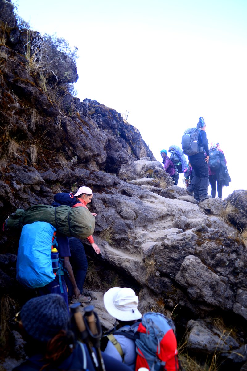 Climbers scrambling up the rock of the Barranco Wall, porters among them
