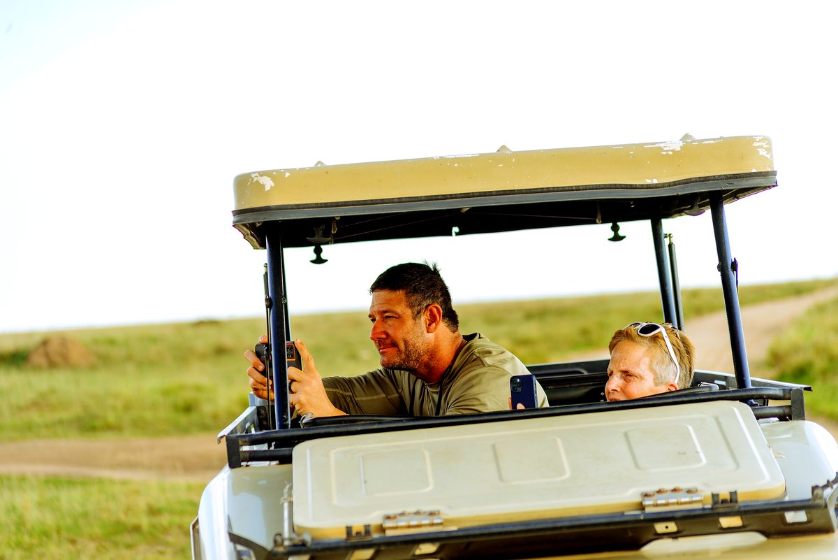A guide and a guest in a safari vehicle on a game drive