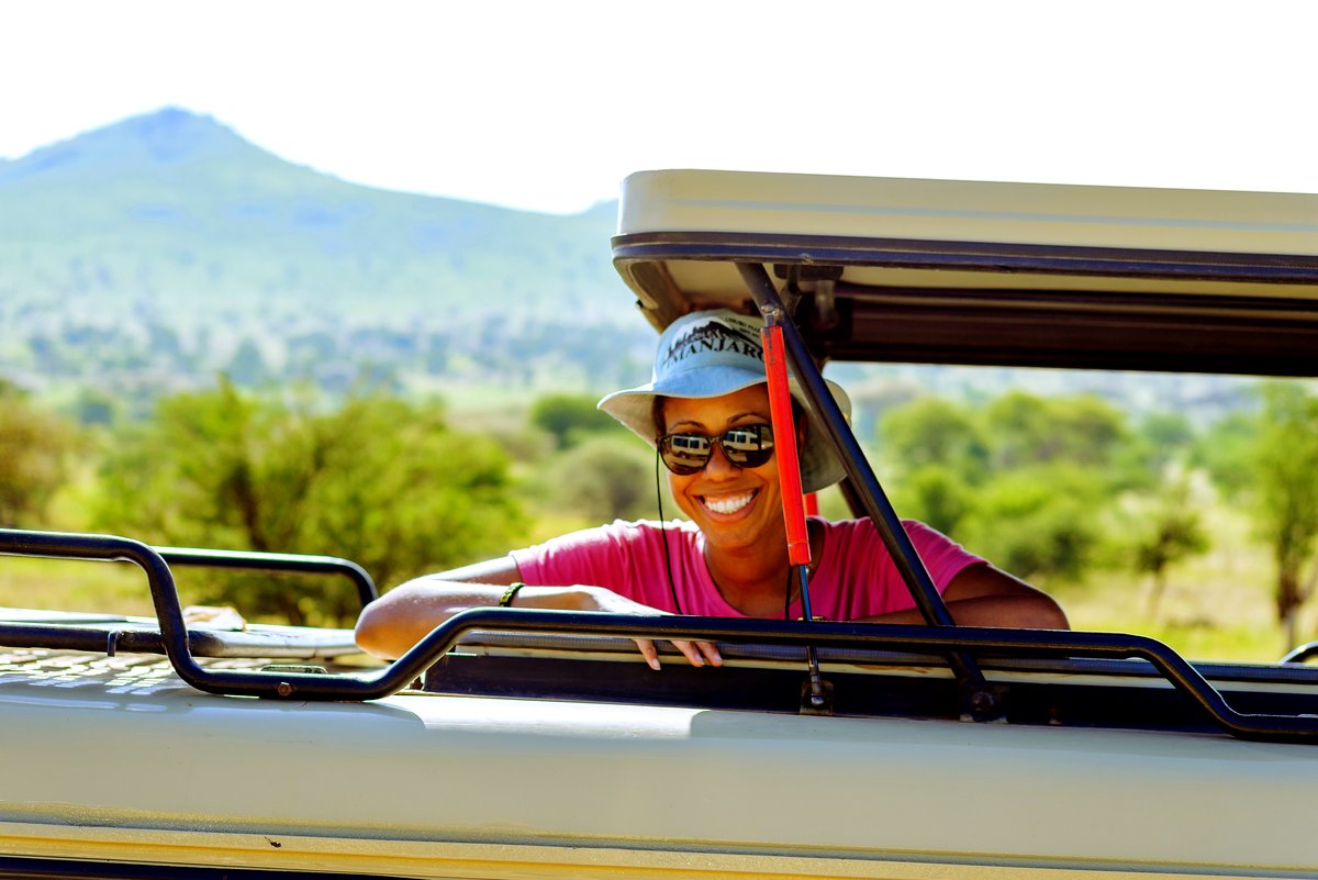 A guest in a safari vehicle with mountains in the distance
